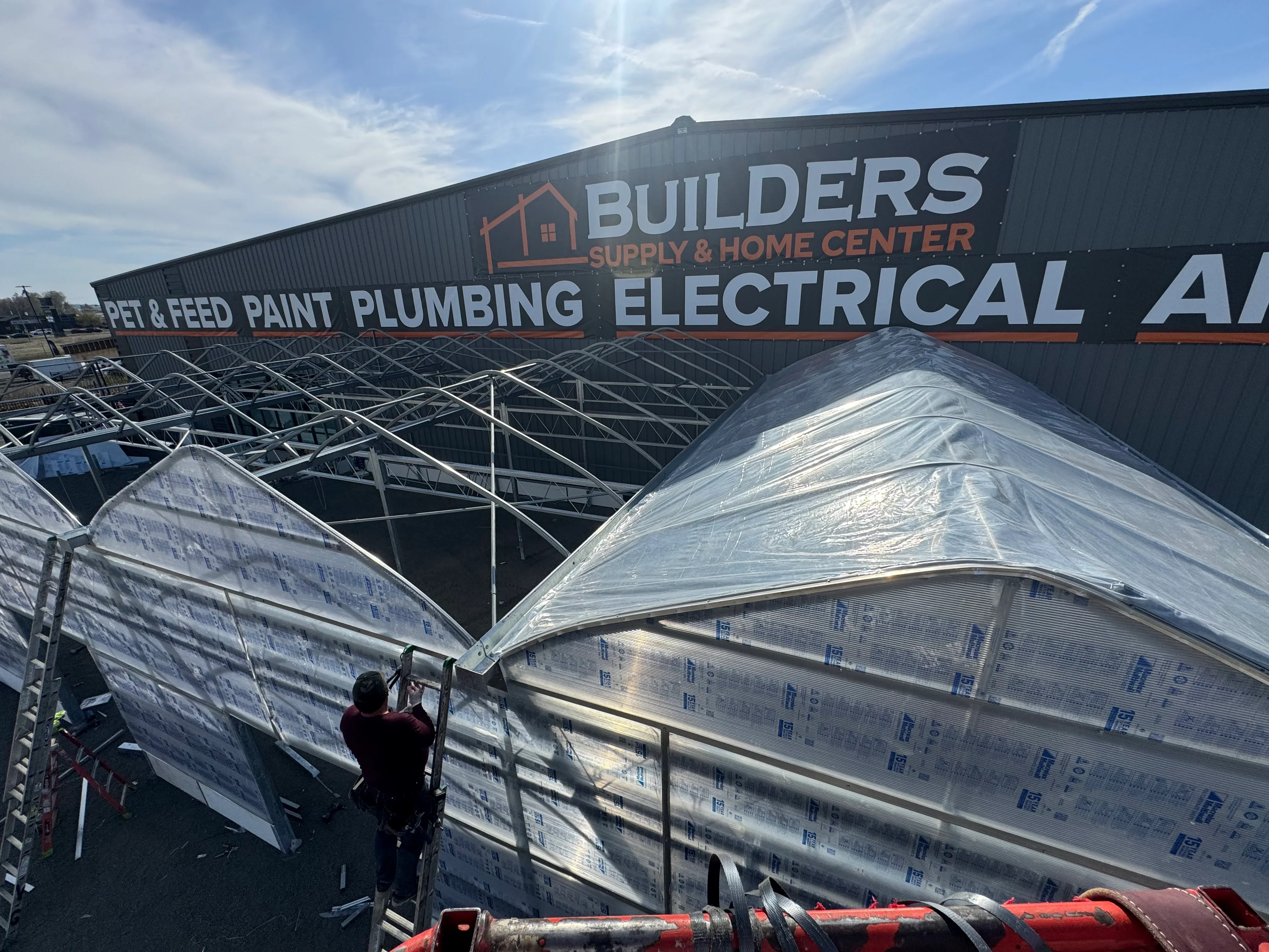 Steel truss framing with white weather-protective membrane during commercial roof installation