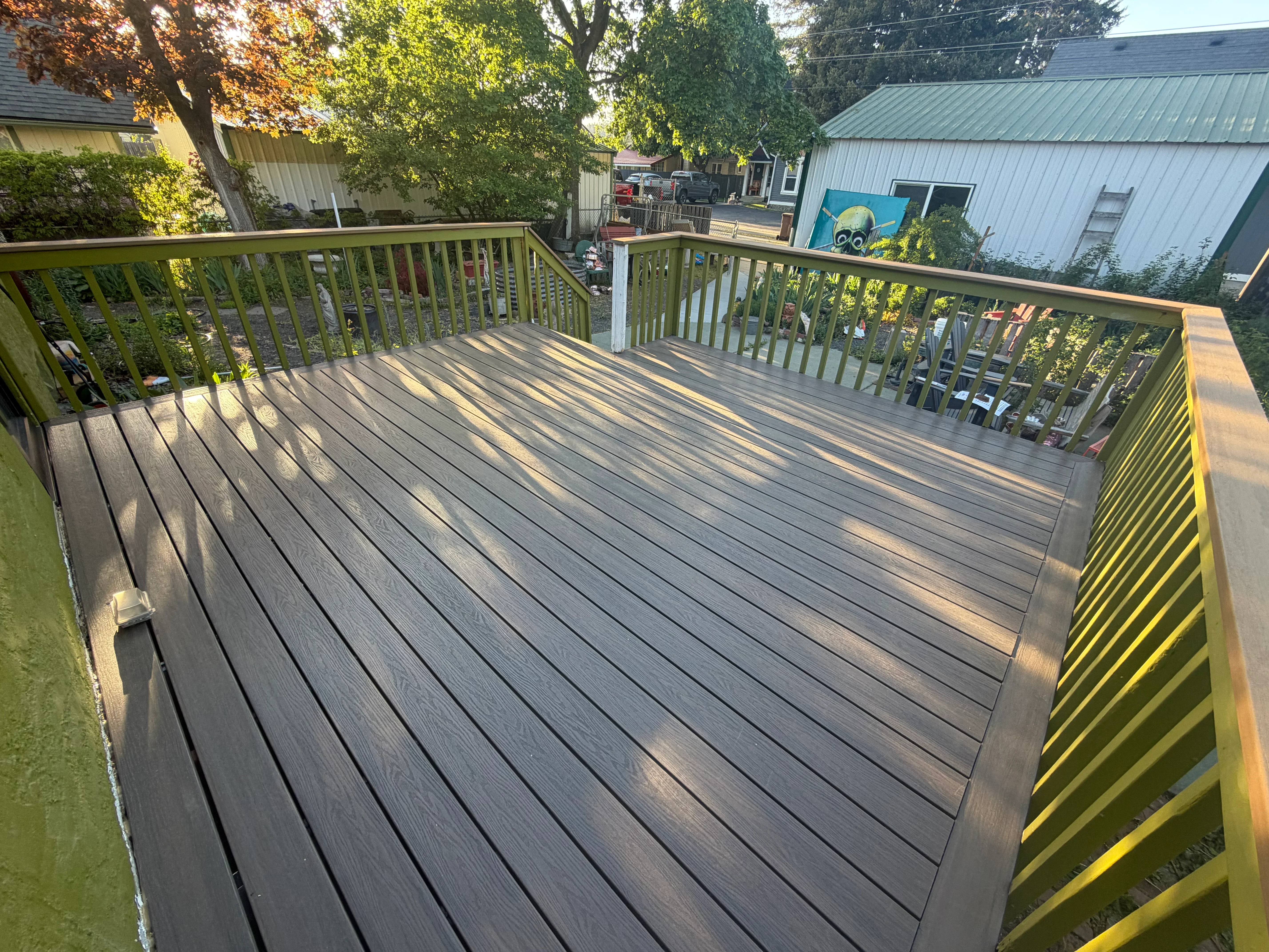 Gray composite deck with yellow wooden railings and balusters, linear board pattern